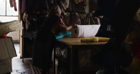 Woman Organizing Fabric Rolls in Workshop