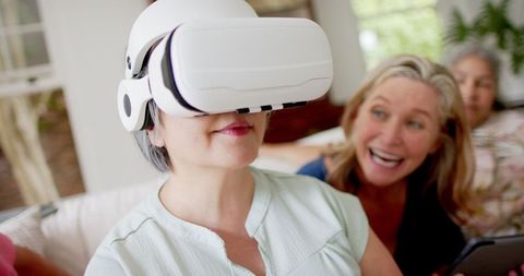 Excited seniors exploring virtual reality together in living room