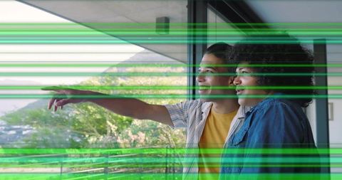 Two males pointing from balcony through glass toward mountain and coastline panorama
