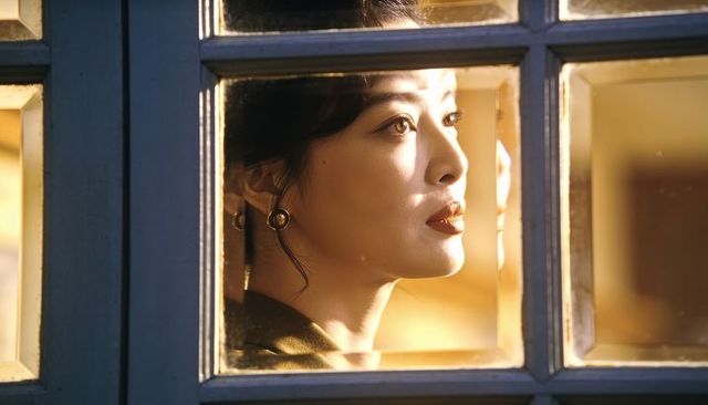 Gazing asian woman framed by window bathed in warm golden light cinematic headshot
