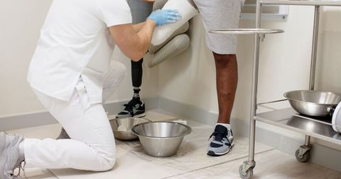 Clinician fitting below-knee prosthetic limb in rehabilitation clinic