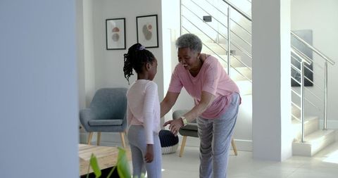 African american grandmother playing with granddaughter in sunlit modern living room