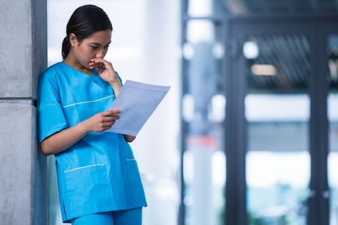 Healthcare professional reading diagnostic report in hospital corridor