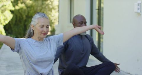 Mature couple practicing gentle yoga and stretching on sunlit walkway for mindful wellness
