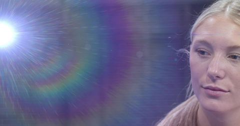 Young woman posing under rainbow lens flare with studio spotlight and soft backlight