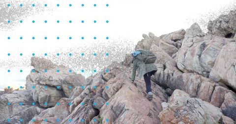 Adventurous hiker climbing rugged coastal rocks