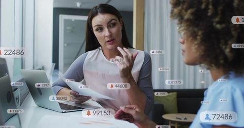 Businesswomen discussing social media analytics and engagement with notification overlays