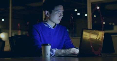 Focused Asian Professional Working Late Night on Laptop in Modern Office