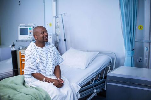 Smiling patient sitting on hospital bed in medical gown