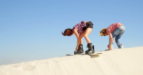 Adventurous Couple Sandboarding on Sunny Dunes
