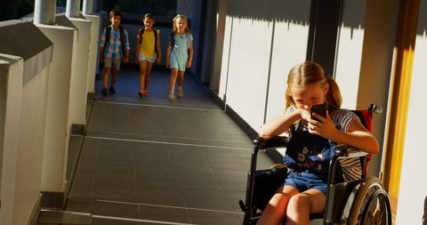 Young Girl in Wheelchair Using Phone in School Corridor - Download Free Stock Images Pikwizard.com