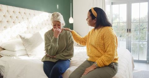 Daughter providing comfort to crying senior mother