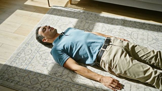 Man lying on rug basking in sunlight in minimalist living room