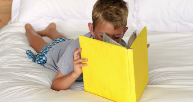 Young Boy Reading Book on Bed with Yellow Cover - Download Free Stock Images Pikwizard.com