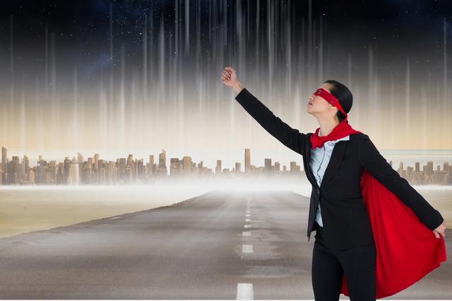 Businesswoman dressed in superhero costume standing on deserted road with city skyline and night sky. Red cape flying, one arm raised, symbolizing determination and empowerment. Useful for themes of leadership, professional success, and ambition in corporate environment.