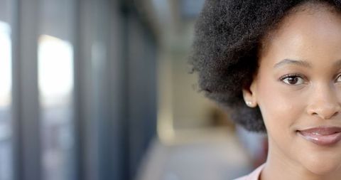 Confident African American Woman Smiling in Modern Office Hallway