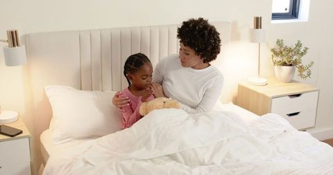 Mother Comforts Child in Warm Bedtime Moment with Teddy Bear