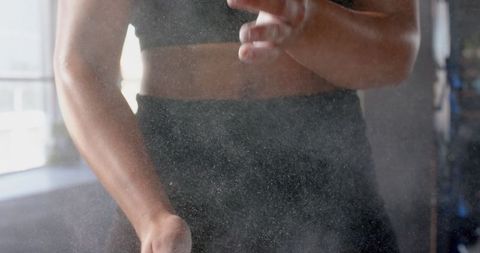 Athletic woman clapping chalk hands in gym