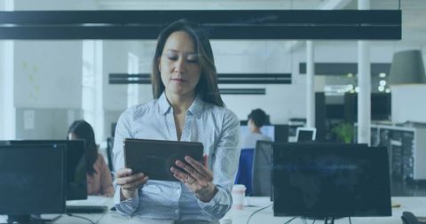 Female professional using tablet in modern open-plan office with coworkers