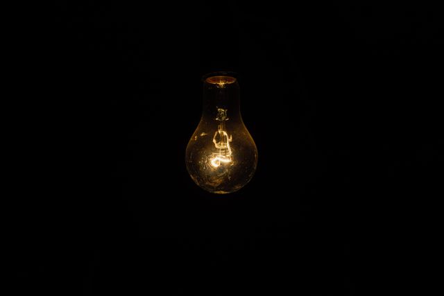 Dimly Glowing Incandescent Light Bulb in Darkness - Download Free Stock Photos Pikwizard.com