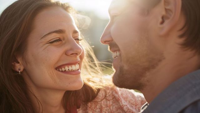 Smiling couple sharing intimate golden hour moment, backlit faces and warm sunlight
