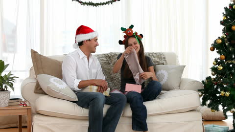 Cheerful Couple Enjoying Gift Exchange During Christmas at Home