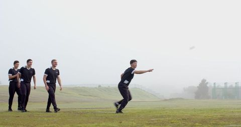 Young male athletes throwing disc in mystical foggy field