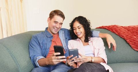 Happy Couple Relaxing on Sofa Using Smartphones