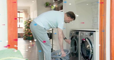 Middle-aged man loading washing machine in cozy holiday laundry nook