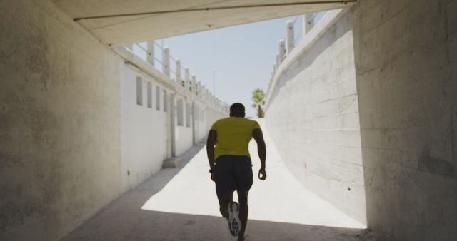 Athletic man running through urban tunnel in bright sunlight - Download Free Stock Images Pikwizard.com