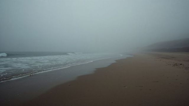 Misty Coastal Landscape with Gentle Waves and Sandy Beach
