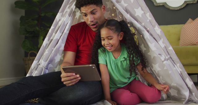 Happy biracial father and daughter using tablet together. domestic lifestyle, spending free time at home.