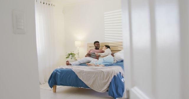 Couple enjoying quality time together in a comfortable bedroom. Useful for advertisements promoting home furniture, bedding companies, or any marketing emphasizing warm and healthy relationships. It can be used in lifestyle blogs, relationship advice articles, or interior design inspiration.