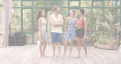 Smiling fitness group standing barefoot in sunlit greenhouse studio with tropical plants