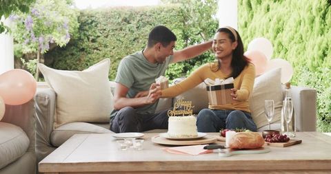 Young Couple Celebrating Birthday with Cake and Gifts on Patio