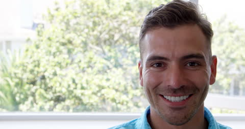 Caucasian Man Smiling Brightly Indoors Near Large Window