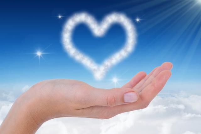 Hand holding heart-shaped cloud in blue sky with light flair. Ideal for themes of love, hope, spirituality, and dreamlike concepts. Suitable for website banners, inspirational posters, greeting cards, and social media graphics.