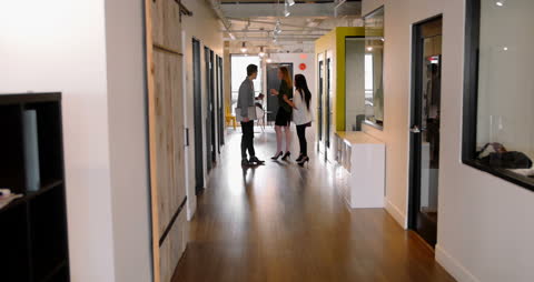Diverse Team Engaging in Workplace Conversation in Modern Office Corridor