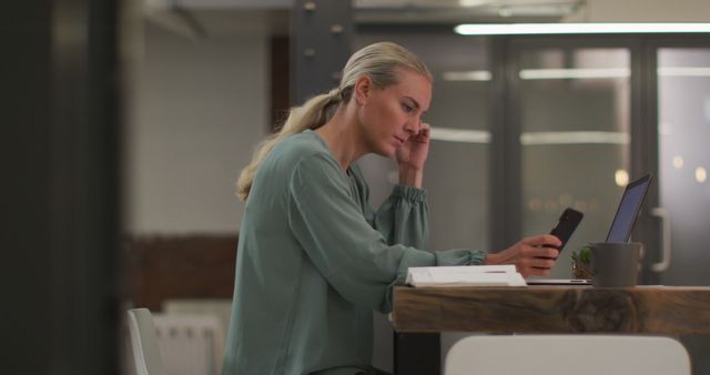 Focused Businesswoman Working Late with Smartphone and Laptop in Modern Office - Download Free Stock Images Pikwizard.com