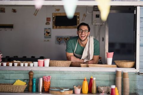 Cheerful male vendor at rustic outdoor food concession stand