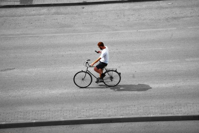 Young Man Riding Bicycle on Road while Using Smartphone - Download Free Stock Photos Pikwizard.com