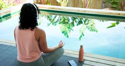 Woman Practicing Meditation by Tranquil Poolside in Natural Setting