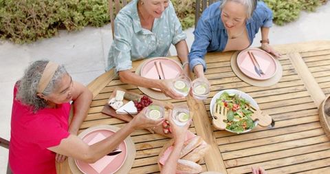 Senior Friends Enjoying Outdoor Meal Toasting Over Salad and Cheese