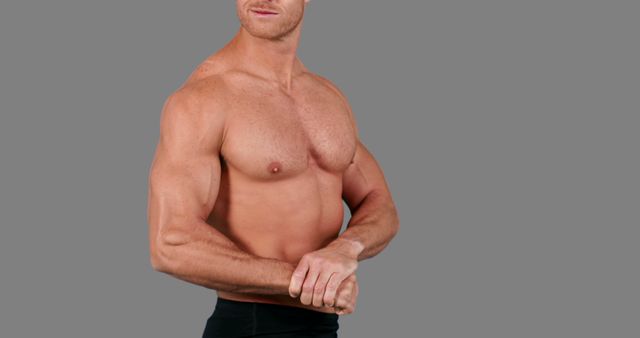 A muscular Caucasian man is showcased against a grey background, with copy space. His physique highlights fitness and strength, emphasizing a healthy lifestyle and bodybuilding.
