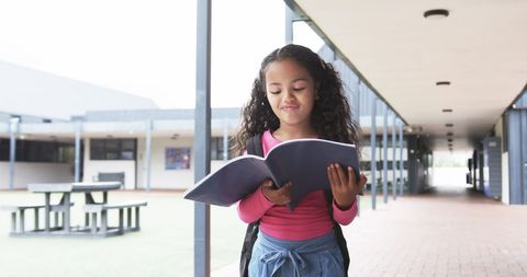 Young Girl Reading Book in School Corridor with Focused Expression - Download Free Stock Images Pikwizard.com