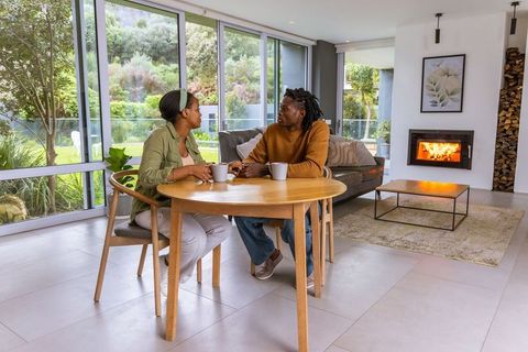 African american couple enjoying coffee at round wooden dining table by large windows