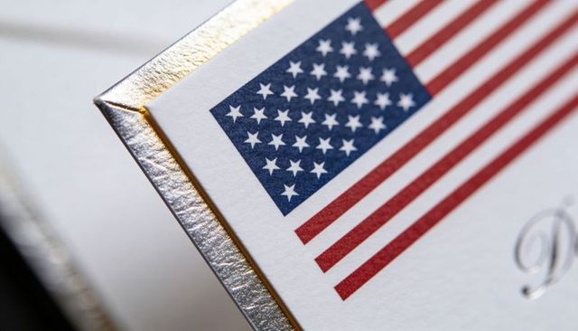 Close-up us flag on luxury invitation corner featuring silver metallic edge and gold foil trim