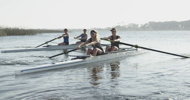 Young Caucasian women rowing in sync on a serene lake - Download Free Stock Photos Pikwizard.com