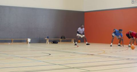 Diverse male basketball teammates warming up sprinting and sliding on indoor court during drill