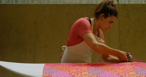 Craftswoman surfboard maker cutting colorful fabric